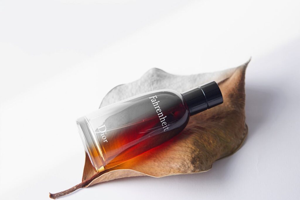 Elegant Dior Fahrenheit perfume bottle displayed artfully on a dried leaf.